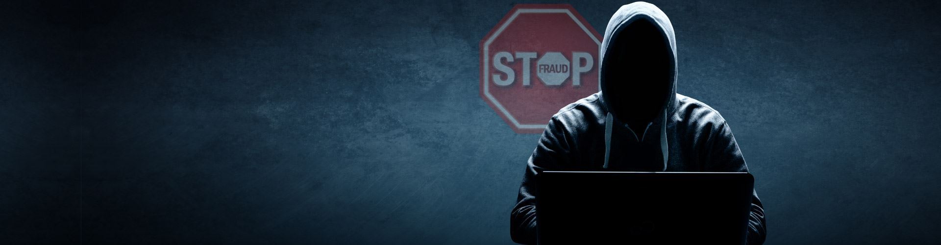 Stop Payment Fraud and protect your business from risk. Cyber criminal/hacker on pc in the dark with Stop Fraud logo behind him.